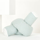 Eine Wickeltischrolle Musselin in Grün mit goldenen Punkten von KraftKids GmbH liegt vor einem minimalen weißen Hintergrund.