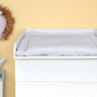 Ein KraftKids Wickelaufsatz weiß für schmale 3er/4er MALM Kommode steht an einer hellgelben Wand, mit einem weichen, gepunkteten Pad. Über dem Wickelplatz hängt ein Plüsch-Pferdekopf, daneben eine weiße Box mit Sternkissen in diesem gemütlichen Babyzimmer.