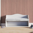 Die KraftKids Kindersitzbank weiß mit Sitzauflage steht vor einer holzgetäfelten Wand, mit schwarzen Turnschuhen und rosa Schuhen auf dem hellen Boden und ist damit ideal für jedes Kinderzimmermöbel-Arrangement.