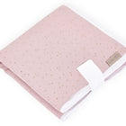 Eine kompakte Reisewickelunterlage Musselin goldene Punkte auf Rosa von KraftKids, gefaltet und mit einem weißen Band gesichert, zeigt winzige goldene Punkte auf blassem Rosa und einem beigen Anhänger - perfekt als platzsparende Wickelauflage für unterwegs.