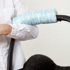 Eine Person in einem weißen Hemd hält den Griff des Kinderwagens, der mit der KraftKids Armschoner Babyschale in Blau mit weißen Pfeilmustern bedeckt ist.