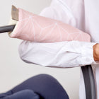 Eine Person mit weißem Hemd hält eine Babyschale mit einer KraftKids Armschoner Babyschale in weißer dünner Diamante auf Altrosa, mit Klettverschluss für zusätzlichen Komfort am Griff.