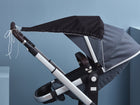 Der KraftKids Sonnensegel Unischwarz ist ein modernes Kinderwagenverdeck in Schwarz und Grau, im Profil auf hellblauem Hintergrund, mit weißen Schnüren und bietet optimalen Sonnenschutz für Ihr Baby.