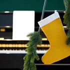 Eine KraftKids Weihnachtssocke Doppelkrepp Gelb Senf hängt an einer geschmückten, mit grüner Girlande drapierten Leiter, während im Hintergrund ein Klavier und geöffnete Notenblätter sanft verschwimmen.