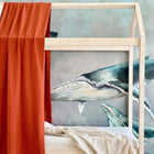 Eine KraftKids Bettbaldachin Doppelkrepp Rot Herbstrot hängt über einem Holzbett vor einem Wandbild mit Walen, und eine beigefarbene Decke sorgt für kuschelige Kinderzimmer Deko.
