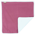 Die KraftKids Wickelunterlage Musselin purpur ist eine rechteckige Stoff-Babydecke mit einfarbig magentafarbener Vorderseite, weißer Einfassung und weißer Rückseite; eine Ecke ist gefaltet, um den Kontrast zu zeigen. Die Decke kann auch als Wickelunterlage verwendet werden, um die Windeln zu wechseln.