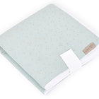 Eine säuberlich gefaltete grüne KraftKids Reisewickelunterlage aus Musselin mit goldenen Punkten, weißem Rand und einem kompakten weißen Band - ideal als platzsparende Wickelunterlage oder Reiseauflage Baby für unterwegs.