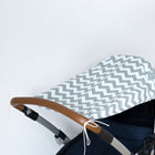 Nahaufnahme eines Kinderwagens mit einem KraftKids Sonnensegel Chevron hellgrau und mint als Sonnenschutz und einem braunen Lenker, vor einem schlichten weißen Hintergrund.