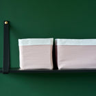 Zwei KraftKids Körbchen Doppelkrepp Rosa in zartem Rosa und Weiß bieten stilvollen Stauraum auf einem minimalistischen schwarzen Regal und setzen einen charmanten Akzent über dem Wickeltisch vor der dunkelgrünen Wand.