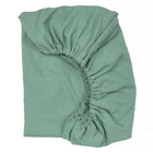 Ein KraftKids Spannbettlaken Doppelkrepp Grün Jade mit elastischen Rändern liegt flach auf einem weißen Hintergrund und ist teilweise gefaltet, so dass die elastischen Ecken sichtbar werden.