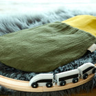 Ein KraftKids Strampelsack Herbst Winter Doppelkrepp Grün Herbstgrün Babyschlafsack ruht auf einem grauen Kunstfellteppich, umgeben von einer hölzernen Spielzeugeisenbahn mit einem weißen und schwarzen Zug.