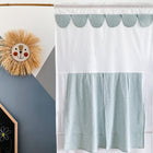 Ein KraftKids Puppentheater Kasperletheater Musselin mint Pusteblumen inkl.. Teleskopstange hängt an einer geometrischen Wand, während links über einer Tafel ein Strohlöwe mit einem lächelnden Gesicht zu sehen ist.