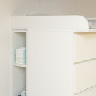 Ein weißes Stauraumregal für Wickeltisch von KraftKids, passend für 3er oder 4er Schubladen der MALM Kommode, bietet praktischen Stauraum neben der Kommode. Bunte Wimpel zieren die Wand in dem hellen, minimalistischen Raum.